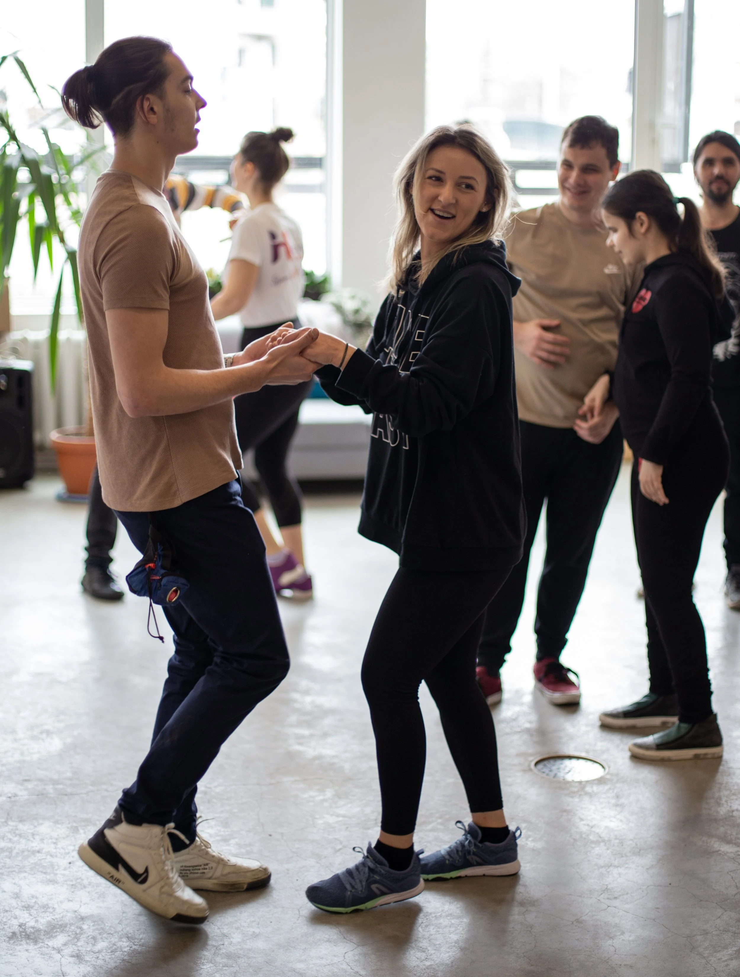Imagine surprinsă în timpul unui atelier de dans. Mai multe persoane dansează în perechi
